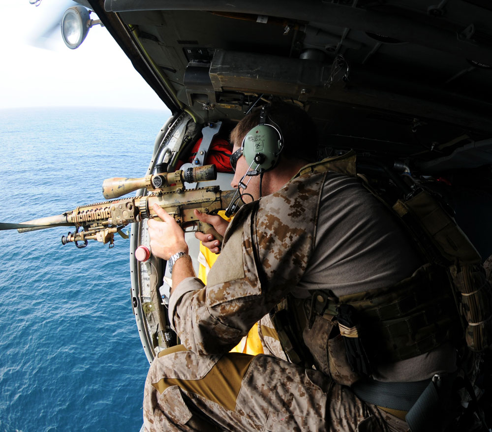 110822-N-XE109-945 ARABIAN SEA (Aug. 22, 2011) A Navy SEAL fires an MK-11 sniper rifle from an MH-60S Sea Hawk helicopter assigned to Helicopter Sea Combat Squadron (HSC) 9, deployed aboard the aircraft carrier USS George H.W. Bush (CVN 77), during a training flight. George H.W. Bush is deployed to the U.S. 5th Fleet area of responsibility on its first operational deployment conducting maritime security operations and support missions as part of Operations Enduring Freedom and New Dawn. (U.S. Navy photo by Mass Communication Specialist Seaman Apprentice Brian Read Castillo/Released)